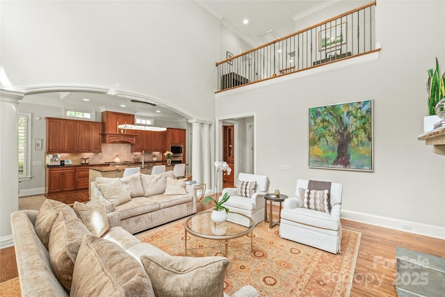 6831 Conservatory Ln, Charlotte, NC 28210 - living room with ornate columns, arched walkways, crown molding, light wood-type flooring, and a high ceiling