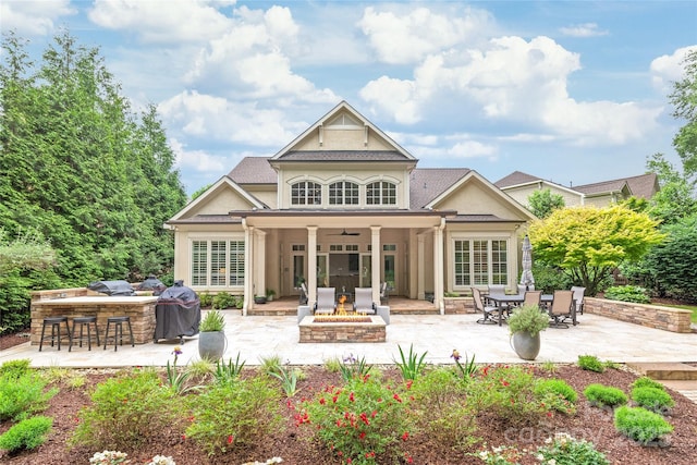 6831 Conservatory Ln, Charlotte, NC 28210 - back of property with a fire pit, a patio area, stucco siding, a ceiling fan, and exterior kitchen