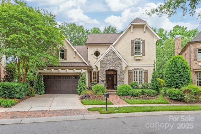 6831 Conservatory Ln, Charlotte, NC 28210 - french country style house with stucco siding, concrete driveway, stone siding, and an attached garage