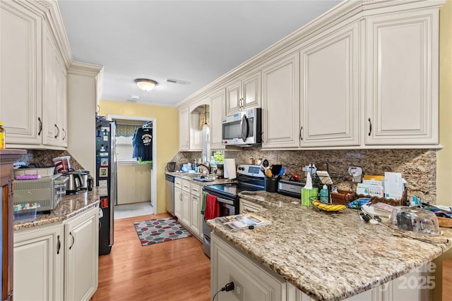 157 E Meadowview Dr, Statesville, NC 28625 - kitchen featuring stainless steel appliances, light wood-type flooring, decorative backsplash, a sink, and a peninsula