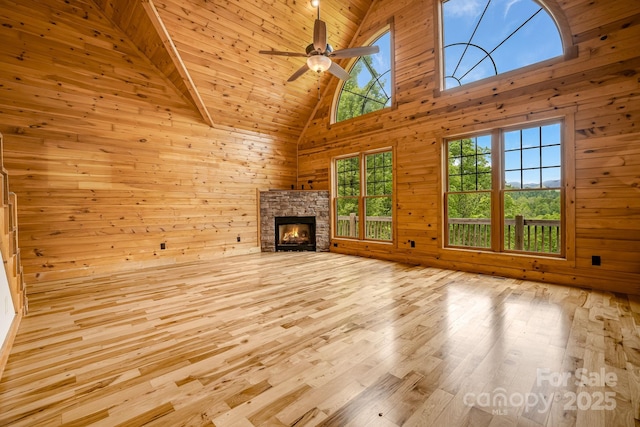 110 Mailon King Rd, Leicester, NC 28748 - unfurnished living room with a stone fireplace, wood walls, high vaulted ceiling, a ceiling fan, and wood finished floors