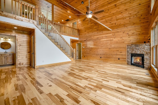 110 Mailon King Rd, Leicester, NC 28748 - unfurnished living room with wooden walls, hardwood / wood-style flooring, a ceiling fan, a fireplace, and stairs