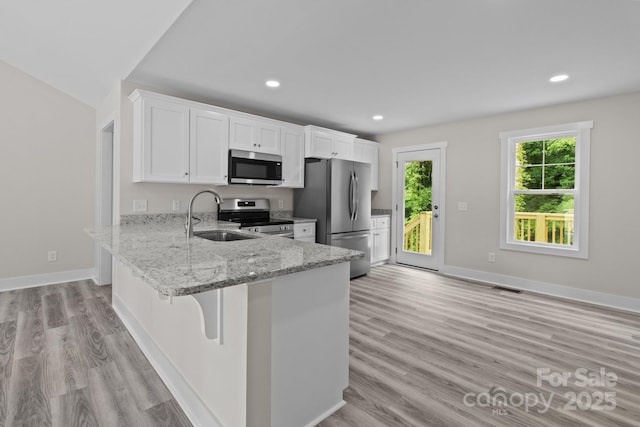 894 Oval St, Kannapolis, NC 28081 - kitchen featuring stainless steel appliances, a sink, light stone countertops, white cabinets, and light wood finished floors