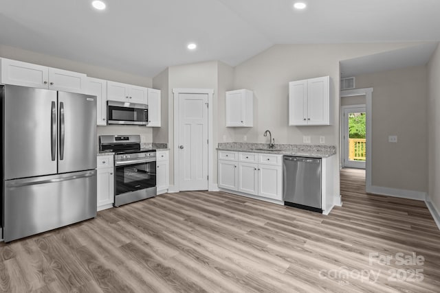 896 Oval St, Kannapolis, NC 28081 - kitchen featuring stainless steel appliances, lofted ceiling, white cabinetry, light wood finished floors, and light stone counters