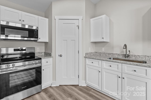896 Oval St, Kannapolis, NC 28081 - kitchen featuring appliances with stainless steel finishes, a sink, light wood finished floors, white cabinetry, and light stone counters