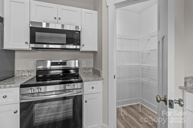 896 Oval St, Kannapolis, NC 28081 - kitchen featuring appliances with stainless steel finishes, light wood-type flooring, white cabinetry, and light stone countertops
