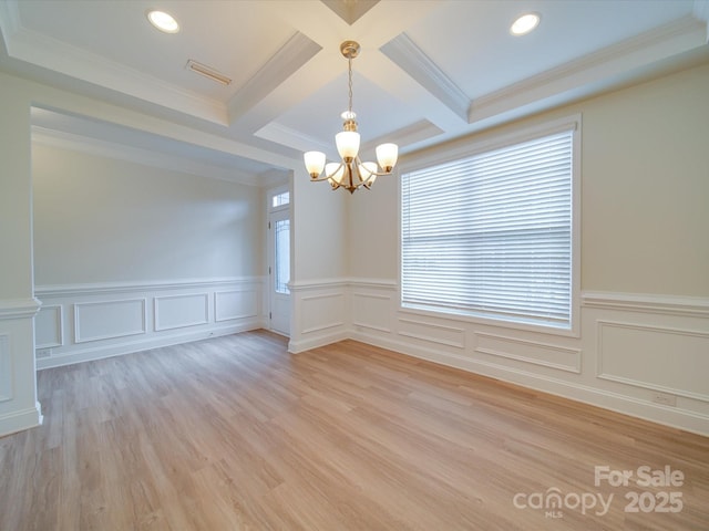 spare room featuring beamed ceiling, a chandelier, a wainscoted wall, coffered ceiling, and light wood-type flooring