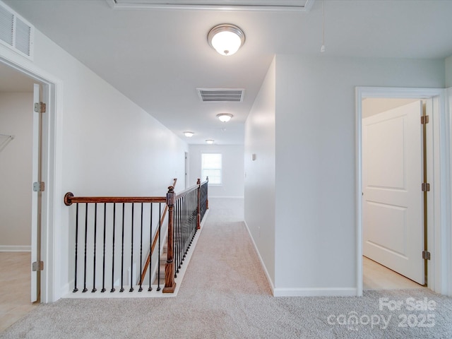 hall featuring attic access, an upstairs landing, carpet flooring, and baseboards