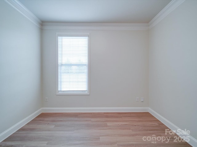 spare room with ornamental molding, light wood-type flooring, plenty of natural light, and baseboards