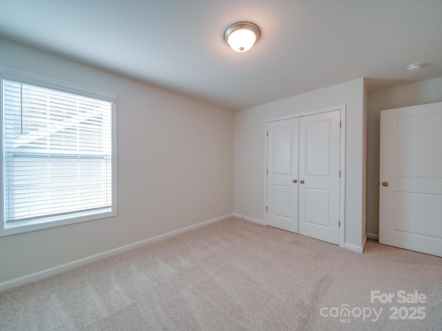 unfurnished bedroom with carpet flooring, a closet, and baseboards