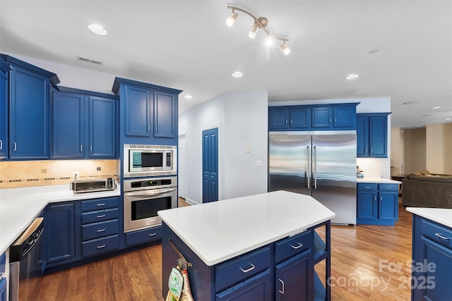 5418 Commodore Pl, Clover, SC 29710 - kitchen featuring built in appliances, blue cabinetry, wood finished floors, a kitchen bar, and light countertops