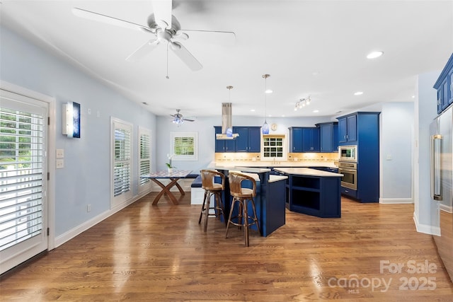 5418 Commodore Pl, Clover, SC 29710 - kitchen with blue cabinets, stainless steel appliances, a center island, ceiling fan, and a kitchen bar