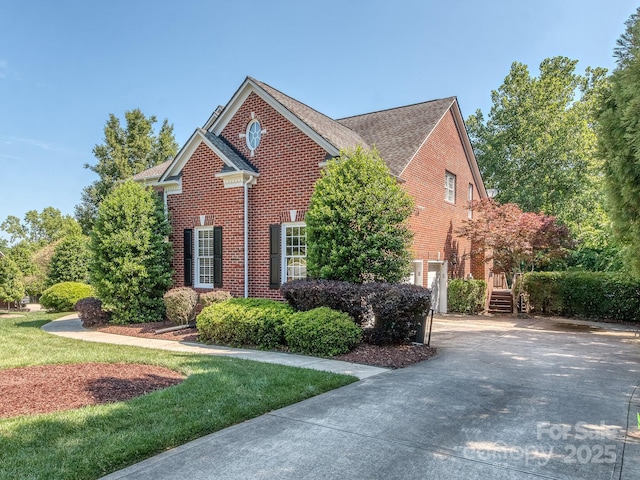 view of front of property featuring brick siding, concrete driveway, and a shingled roof