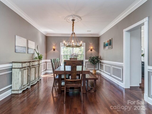 dining room with a chandelier, a decorative wall, ornamental molding, dark wood finished floors, and a wainscoted wall