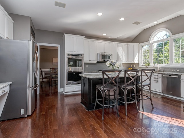 kitchen with stainless steel appliances, light stone counters, dark wood-style flooring, recessed lighting, and lofted ceiling