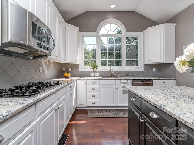 kitchen with stainless steel microwave, black gas stovetop, dark wood finished floors, a sink, and vaulted ceiling