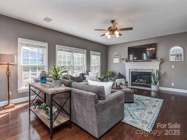 living room with ceiling fan, wood-type flooring, a fireplace, and baseboards