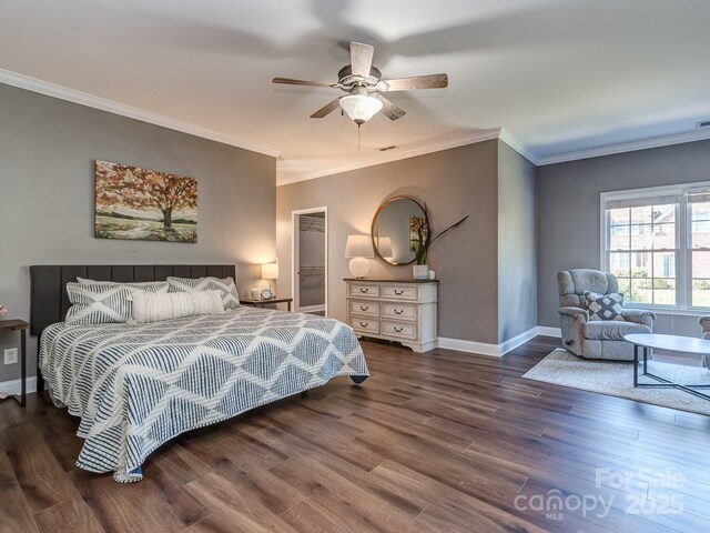 bedroom with wood finished floors, baseboards, ornamental molding, a walk in closet, and a ceiling fan