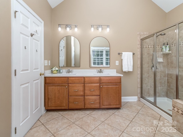 bathroom featuring lofted ceiling, a stall shower, tile patterned floors, double vanity, and baseboards