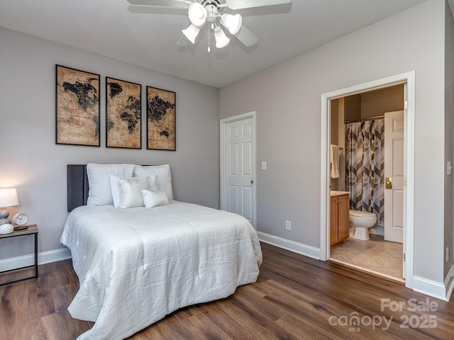 bedroom featuring baseboards, wood finished floors, ensuite bath, and ceiling fan