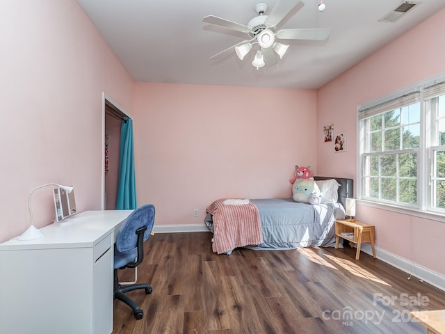 bedroom with baseboards, wood finished floors, an office area, and a ceiling fan