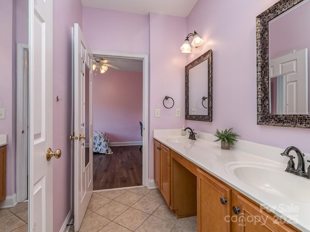 ensuite bathroom featuring tile patterned flooring, double vanity, ceiling fan, and baseboards