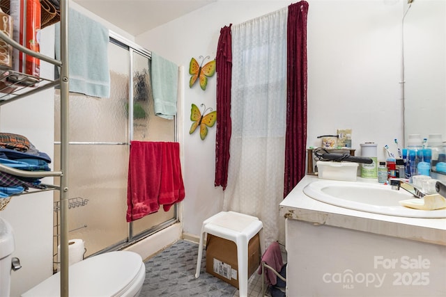 bathroom with toilet, a shower stall, and vanity