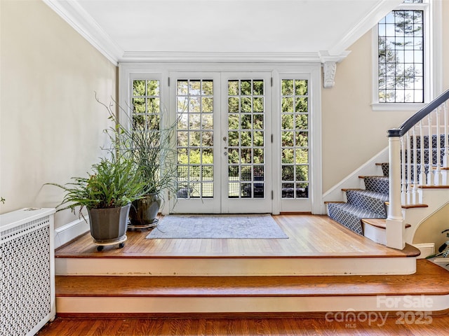 doorway with radiator, crown molding, stairway, wood finished floors, and baseboards