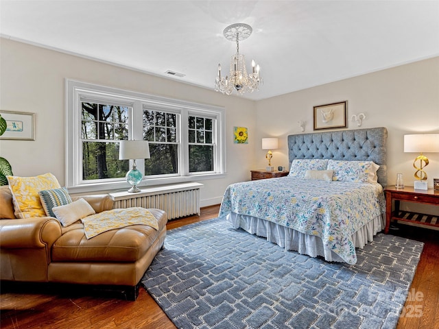 bedroom with radiator heating unit, wood finished floors, and a chandelier