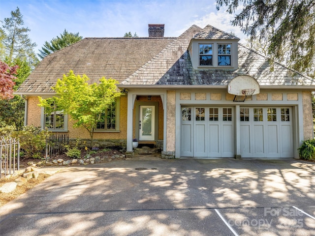 view of front of property with a chimney, concrete driveway, and a garage