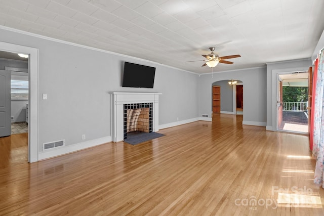 24501 Canton Rd, Albemarle, NC 28001 - unfurnished living room featuring ornamental molding, a ceiling fan, light wood-type flooring, arched walkways, and a tiled fireplace