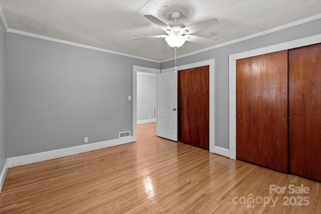 24501 Canton Rd, Albemarle, NC 28001 - unfurnished bedroom featuring two closets, wood finished floors, baseboards, ornamental molding, and ceiling fan