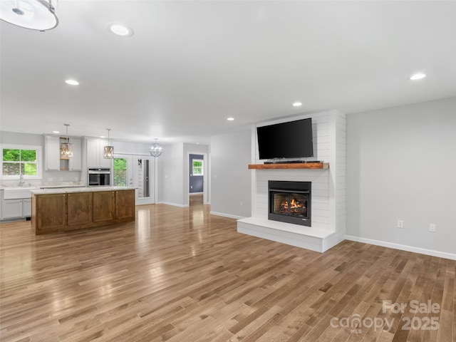 155 Pebble Ridge Rd, Spruce Pine, NC 28777 - unfurnished living room featuring a fireplace, light wood-type flooring, recessed lighting, baseboards, and a sink