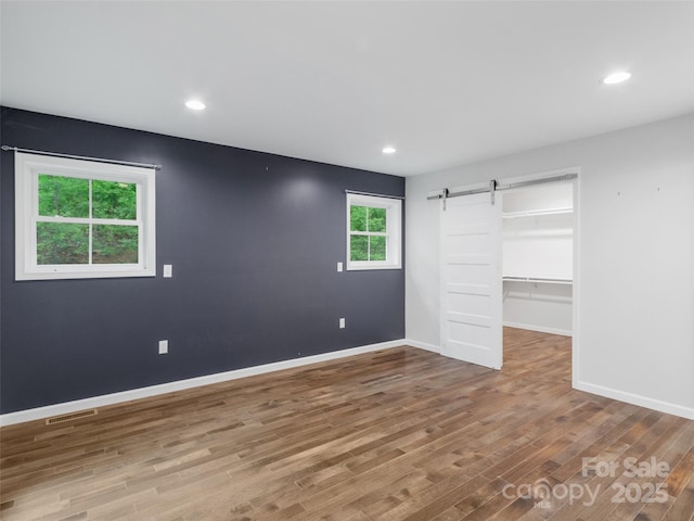 155 Pebble Ridge Rd, Spruce Pine, NC 28777 - unfurnished bedroom featuring a barn door, wood finished floors, baseboards, a spacious closet, and recessed lighting