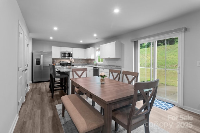 dining room with light wood-type flooring, baseboards, and recessed lighting
