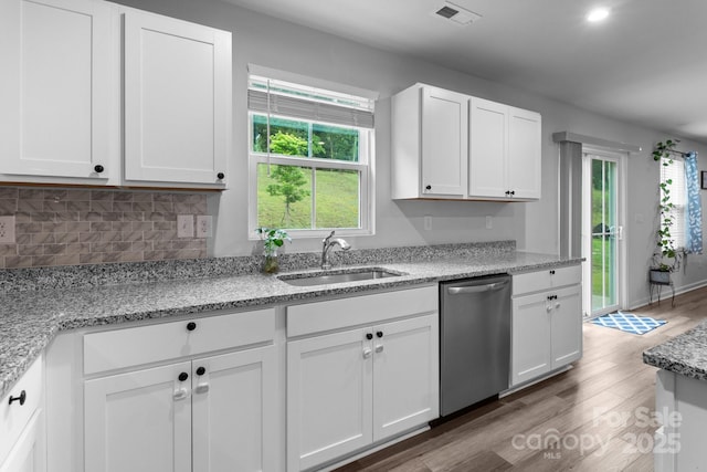 kitchen with dishwasher, a sink, wood finished floors, and white cabinets