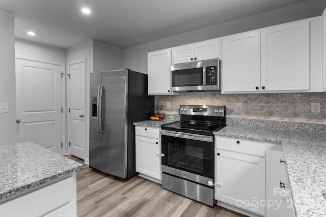 kitchen with stainless steel appliances, light wood-style floors, white cabinetry, recessed lighting, and decorative backsplash