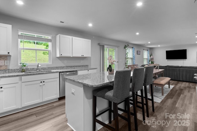 kitchen with dishwasher, a sink, recessed lighting, white cabinets, and light stone counters