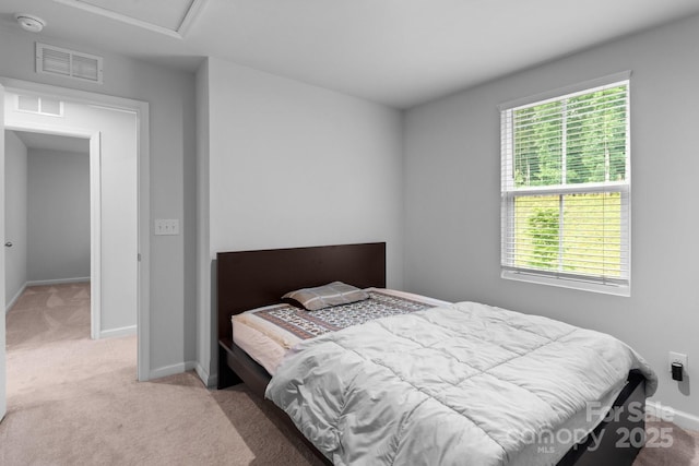 bedroom with light colored carpet, attic access, and baseboards