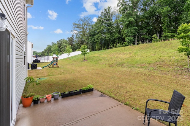 view of grassy yard featuring a patio and a playground