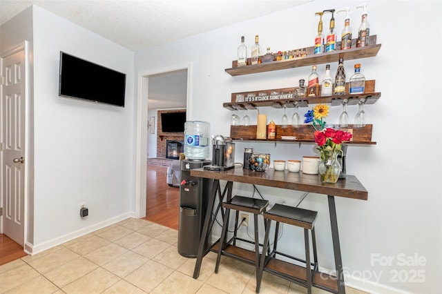 3049 Stablegate Dr, Gastonia, NC 28052 - indoor dry bar featuring a fireplace, baseboards, light tile patterned flooring, and a textured ceiling
