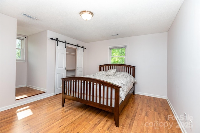 3049 Stablegate Dr, Gastonia, NC 28052 - bedroom with a barn door, light wood-type flooring, baseboards, and a textured ceiling