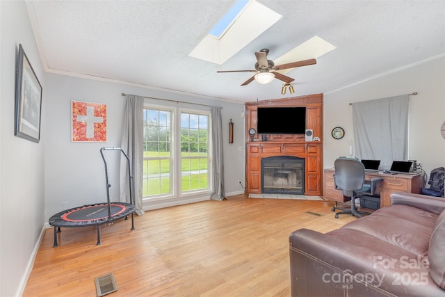 403 Carpenter Parker Ln, Rock Hill, SC 29730 - living room featuring a skylight, light wood-type flooring, ornamental molding, a large fireplace, and a textured ceiling
