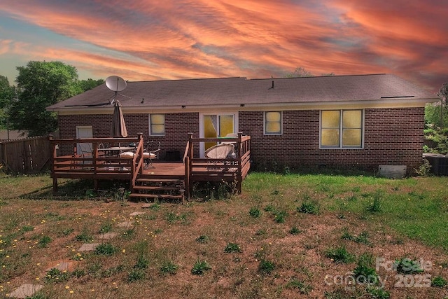 305 Ridge Manor Dr, Raeford Township, NC 28376 - back of house at dusk with a deck, brick siding, central AC, a shingled roof, and fence