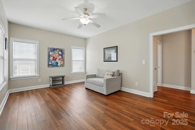 sitting room featuring dark wood-type flooring, a ceiling fan, and baseboards