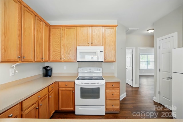 kitchen with white appliances, dark wood-style flooring, and light countertops