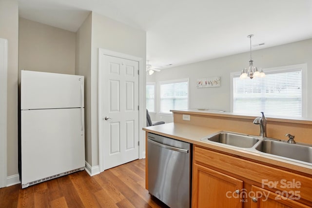 kitchen with freestanding refrigerator, dishwasher, a sink, dark wood-style floors, and brown cabinets