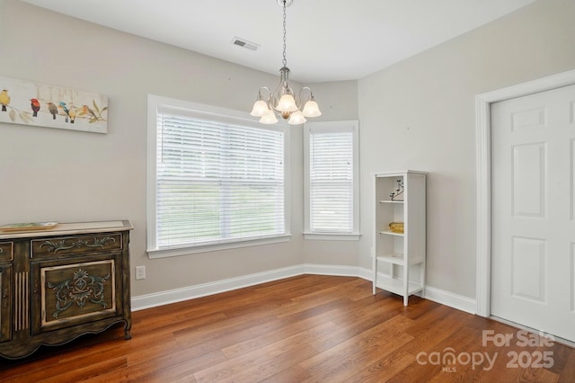 unfurnished dining area featuring a chandelier, wood finished floors, and baseboards