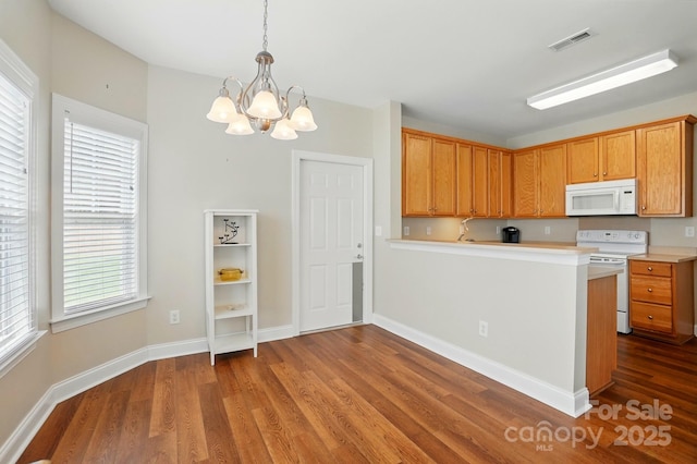 kitchen with white appliances, a chandelier, wood finished floors, and plenty of natural light
