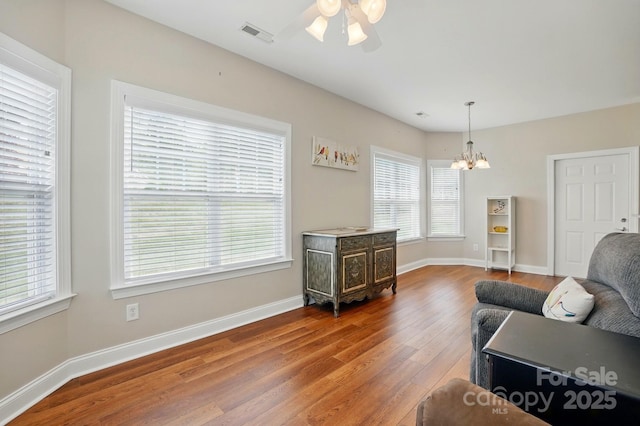 living area with a chandelier, wood finished floors, a ceiling fan, and baseboards